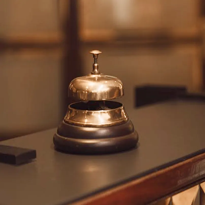 Polished brass concierge bell on a dark wooden desk
