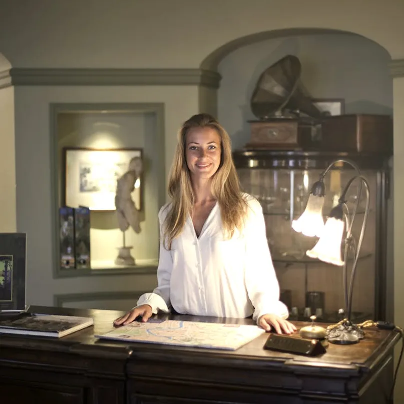 Concierge welcoming a guest at a classic wooden reception desk