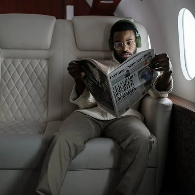 Member reading a newspaper in a quilted leather private jet cabin